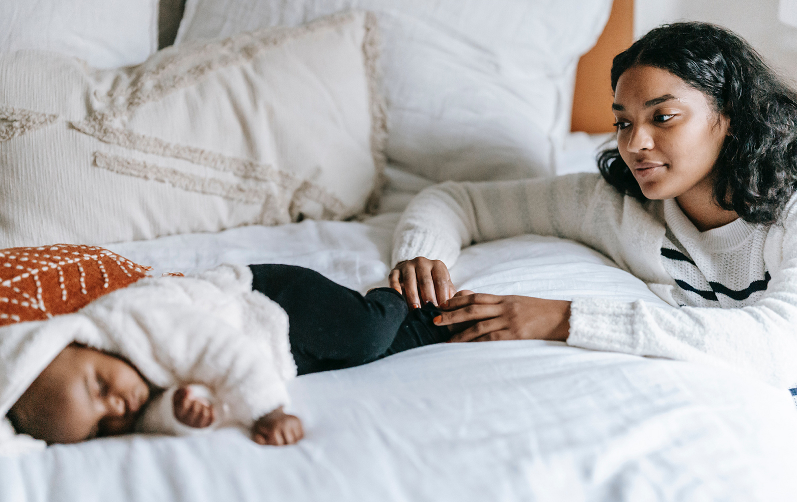 Woman caring for baby laying on bed